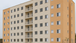 Foto de prédio residencial popular recém-construído, representando imóveis HIS e HMP para compradores e investidores.